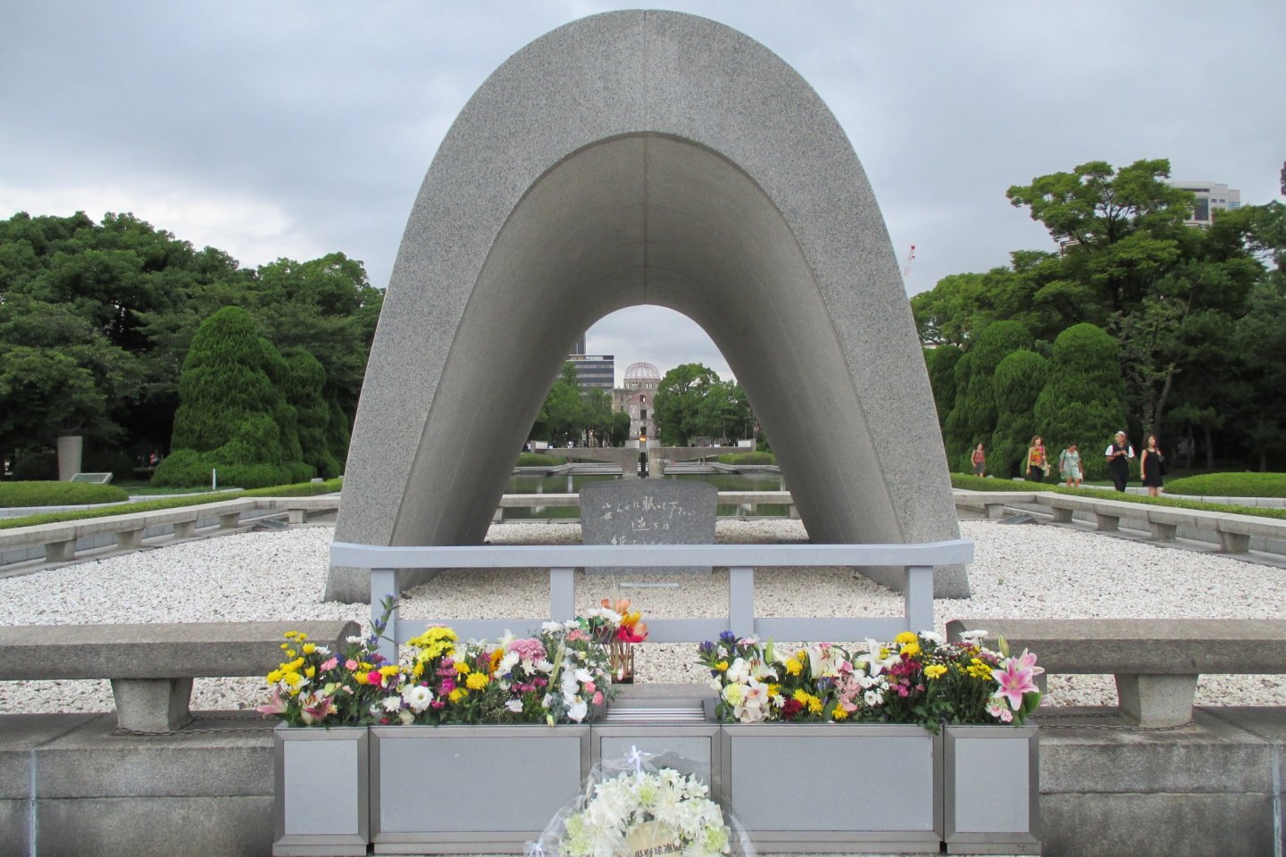 The cenotaph for the A-bomb victims. A chest holds a registry of  victims who have passed. The Peace Flame and the A-bomb Dome can be seen through it.