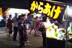 Girls wearing yukata check out the stalls