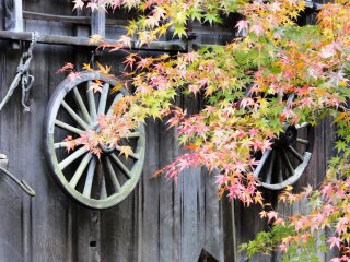 An old wheel hangs on the side of one of the thatched roof homes