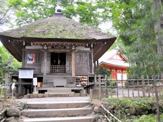 Visitors pray to Fudo Myo-o, the protector of Buddhism and one of the Wisdom Kings, at this thatched roof sub-temple building.