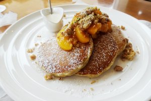 Seasonal pancakes topped with peaches and streusel nut topping