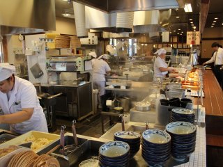 The mesmerizing activity in the kitchen tends to slow down the line of customers that enjoy the show rather than slide their tray to the cash register