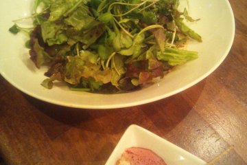 Fresh green lettuce with vinaigrette and the "otoshi" (some might say "extortion") plate