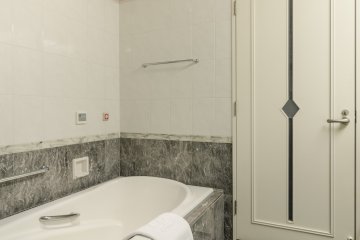 <p>Even the door to the bathroom is stylish, and the lovely stone that lines the walls adds to the classy design.</p>