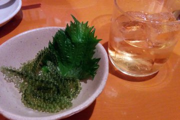 <p>Some plum wine next to the small snack you are given upon sitting. It was the first time I had seen and eaten this Okinawa specialty.&nbsp;</p>