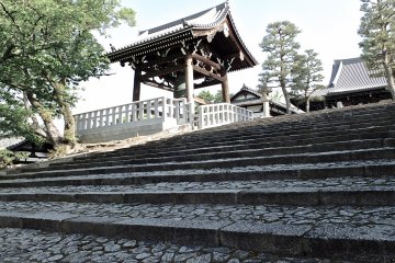 <p>Climbing the stone steps to hall and temple bell (on the left)</p>