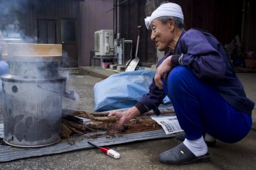 <p>Mr Kato setting up a wood fire to cook rice for dinner</p>