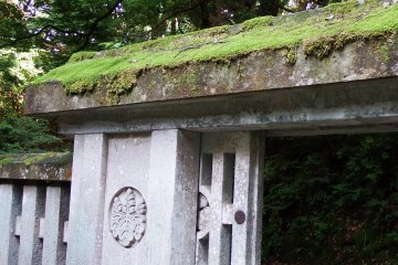 <p>Moss-covered stone roof of the cemetery gate. The crest of &#39;Paulownia of 5-7&#39; is carved along with Matsudaira Family&#39;s crest, &#39;Circle Around Three Hollyhock Leaves&#39;</p>