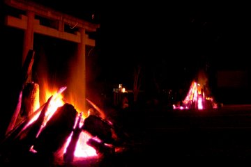 <p>Two large bonfires lit near a torii</p>