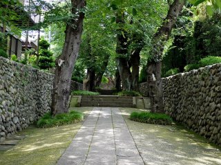 Một lối vào đầy lôi cuốn với nhiều cây xanh, nằm giữa hai bức tường đá