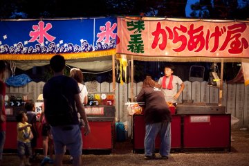<p>Two of the many festival stalls selling food, drinks, games, and goods</p>