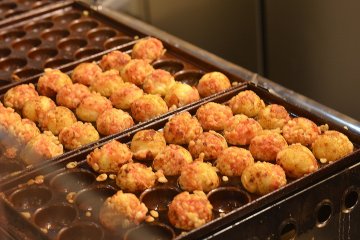 <p>Takoyaki cooking in their special pans</p>