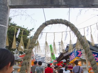 Mọi người đi lại dưới vòng dây thừng đặc biệt được gọi là chinowa-kuguri bên dưới cổng torii bê tông 