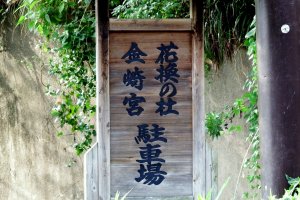 Wooden sign indicating the direction to Kanegasaki Shrine and its parking lot