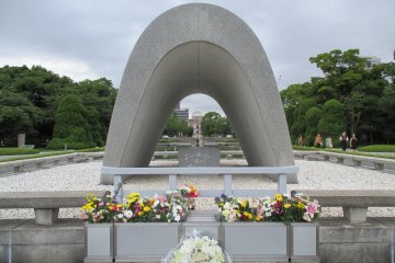 <p>The cenotaph for the A-bomb victims. A chest holds a registry of &nbsp;victims who have passed. The Peace Flame and the A-bomb Dome can be seen through it.</p>