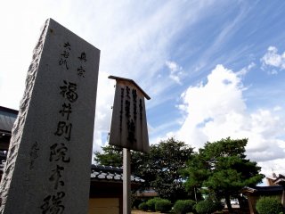 Bảng chỉ dẫn bằng đá của chùa Honzui-ji và cây xanh trên sân vườn