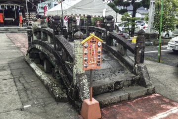 <p>This interesting stone bridge sits in front of the shrine. Unfortunately, no information was provided that I could find explaining its history or significance. However, there is a small sign listing specific cats in the area and the kind of fortune you will encounter if you cross paths with them (Japanese only).</p>