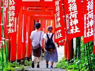 Two visitors gradually disappearing into a thick sea of red torii&nbsp;(gates)