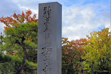 <p>Shougenji Temple&#39;s stone marker standing with colorful autumn leaves in the background</p>