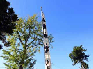 Tall white flag of Maki Shrine fluttering in the wind standing high in the blue sky