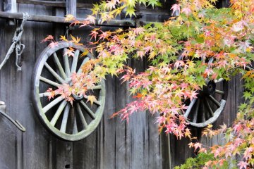 <p>An old wheel hangs on the side of one of the thatched roof homes</p>