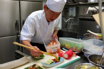 <p>One of the chefs prepares dishes in the kitchen</p>