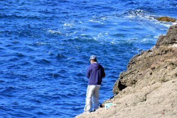 <p>Closer look at a fisherman on the rock</p>