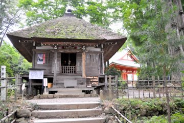 <p>Visitors pray to Fudo Myo-o, the protector of Buddhism and one of the Wisdom Kings, at this thatched roof sub-temple building.</p>