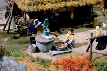 <p>A girl washes persimmons under a water pump in this model</p>