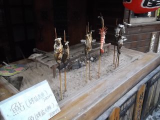 There are lots of places to buy snacks, like barbequed fish on a stick