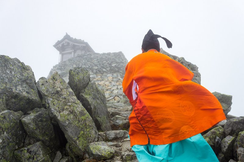 <p>A Shinto priest ascends the final steps to the summit</p>