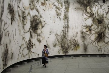 <p>A visitor the the exhibition views the large gunpowder painting by Cai.&nbsp;</p>