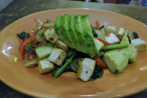 A tofu and veggie scramble, topped with avocado