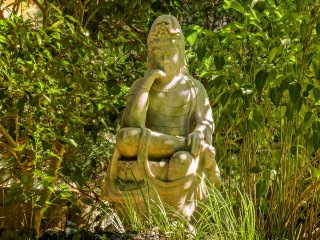 A statue of Gautama Buddha (Shaka Nyorai), sits within Hokokuji&#39;s peaceful stone garden