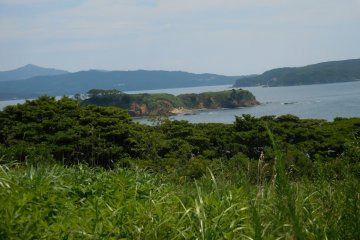 Two islands, the small island (unknown), and Ajishima Island（網地島） on the right hand. The peninsula on the left is Oshikahantou (牡鹿半島). The top of the mountain behind the Oshikahantou is Kinkasan (金華山)