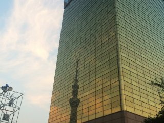 A reflection of Skytree at dusk in the Asahi Beer Tower.
