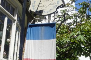 A French tricolor hangs beneath the sign for the restaurant