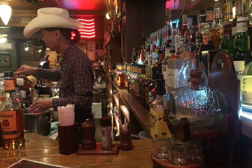 A bartender in a cowboy hat mans the bar area at Steak and Bar Red River in Chiba.