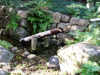 Un shishi-odoshi ( fontaine japonaise) qui se situe le long du lac pr&egrave;s de la maison de th&eacute;
