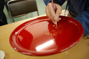 Makie, the painting of lacquerware plates, can be experienced at the Uruwashi-Kan in Kuroe Town. 