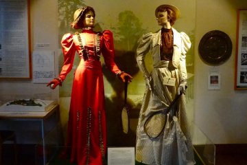 <p>Two female mannequins wearing long skirts and holding small rackets</p>