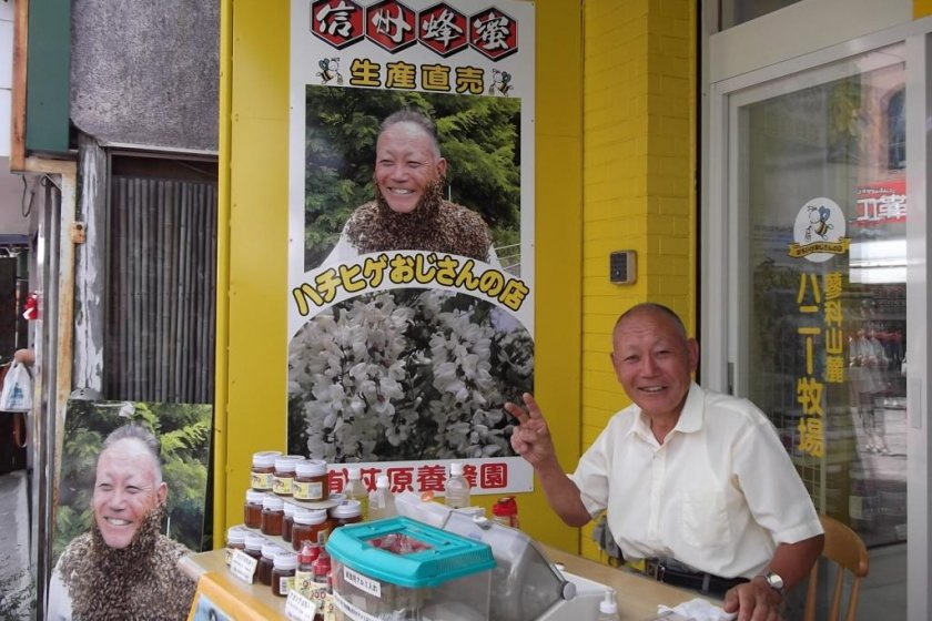 The 'Bee-beard oyaji' outside his shop: note the small plastic box of bees on the table