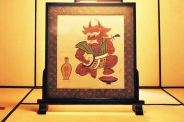 An otsu-e of a mythical goblin playing the shamisen and drinking sake