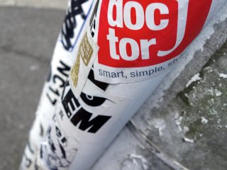 A streetpole is plastered with logo stickers and graffiti insignias