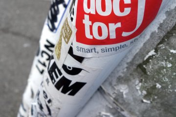 A streetpole is plastered with logo stickers and graffiti insignias