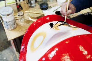 Painting the detail onto a Daruma doll