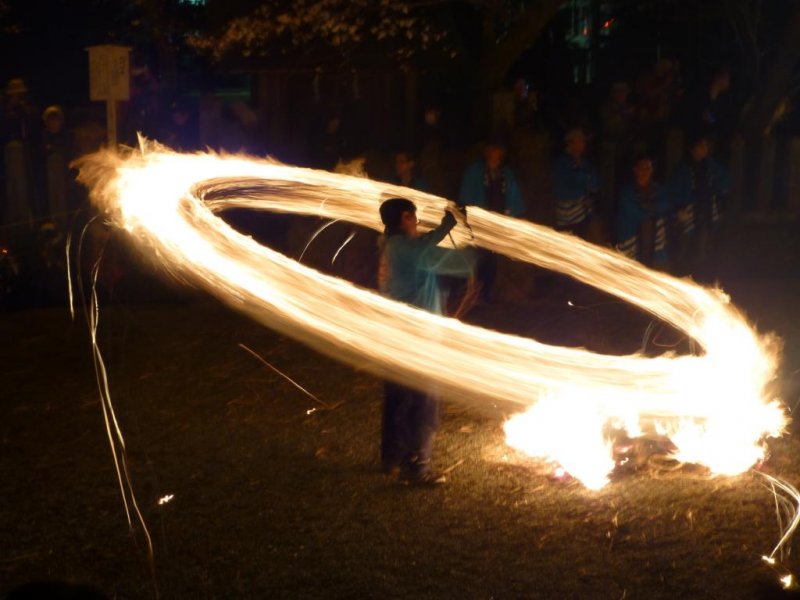 A festival participant swings a fiery torch at the annual Hifuri Shinji at Aso Shrine