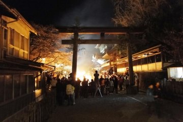 The torii gate of Aso Shrine lit up by the fire's glow