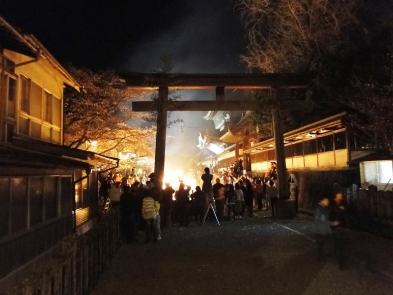 The torii gate of Aso Shrine lit up by the fire's glow