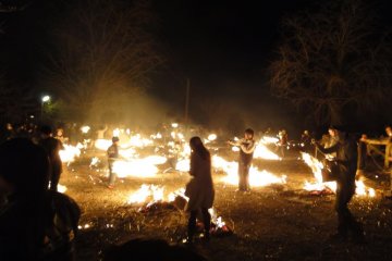 Audience members swing torches in a nearby field